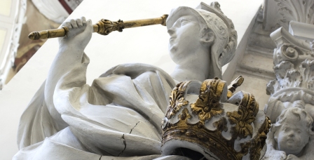 Biała rzeźba trzymająca złotą koronę